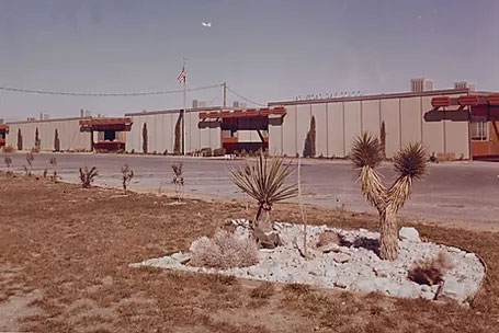 an old photo of the exterior of the Las Vegas Day School campus with desert vegetation in the foreground