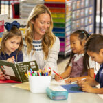 a woman sitting in a Las Vegas Day School classroom smiling as she reads a dr suess book to two young students on either side of her