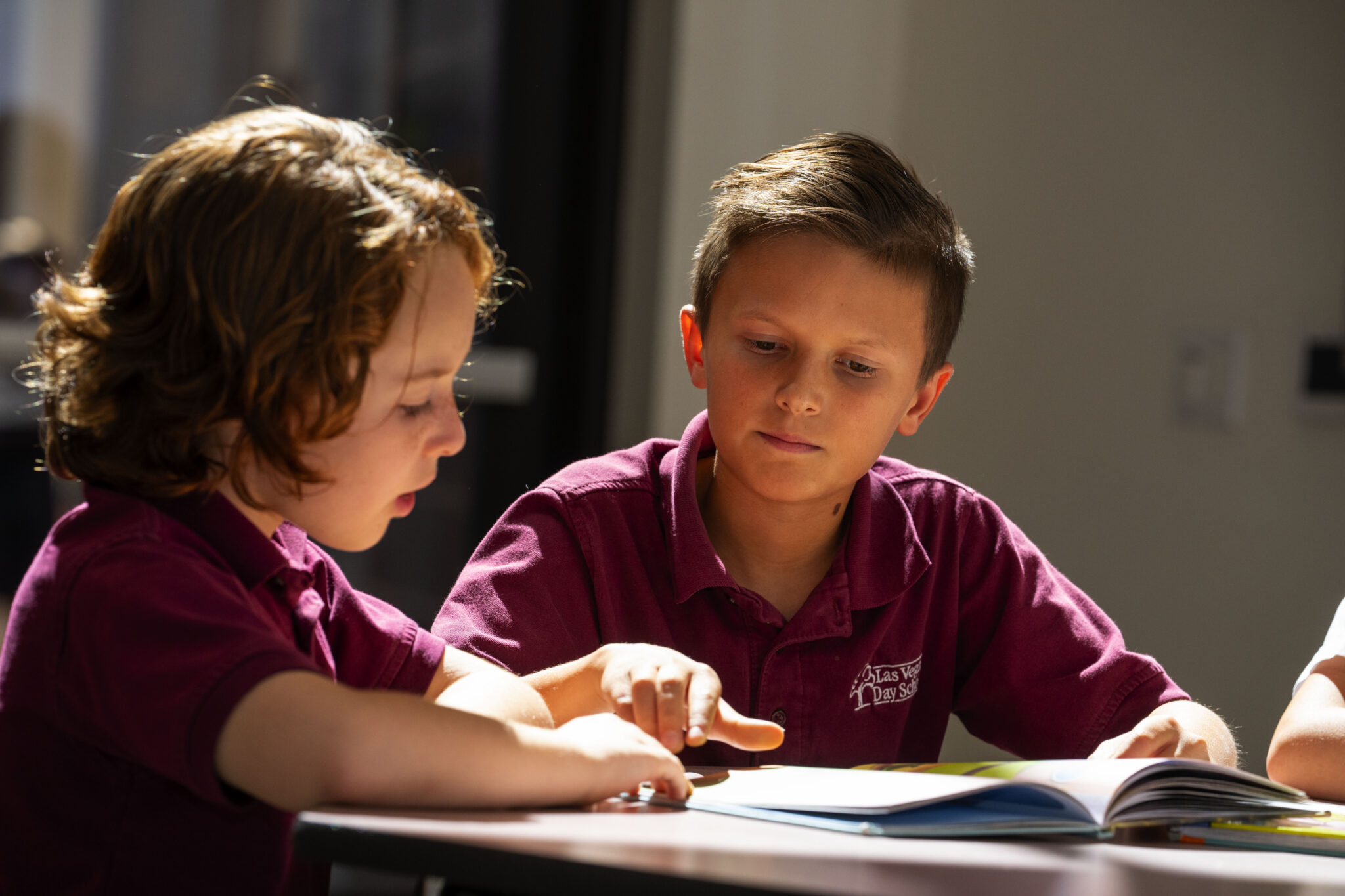 a young student points to a book that another student is reading at Las Vegas Day School