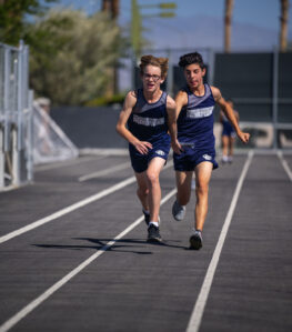2 young Las Vegas Day School athletes passing a relay baton in the middle of a race